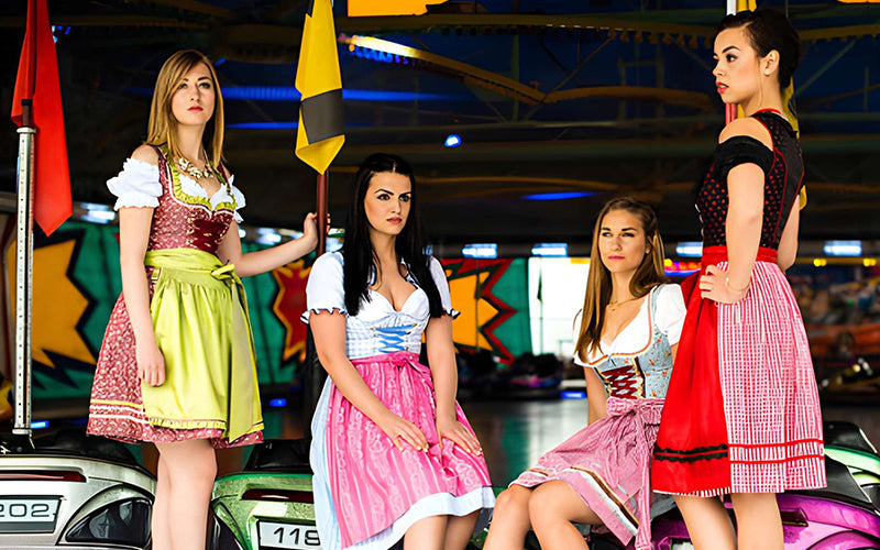 Women wearing colorful dirndl dresses with coordinated bodices, aprons, and accessories, showcasing the 3-3-3 fashion rule for dirndl styling.