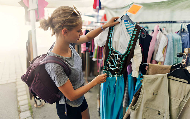 Woman shopping for a traditional dirndl dress at a clothing store, comparing Bavarian outfits and styles.