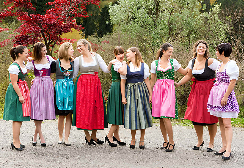 Group of women wearing colorful dirndls with varying skirt lengths, highlighting different Bavarian styles and fit options.