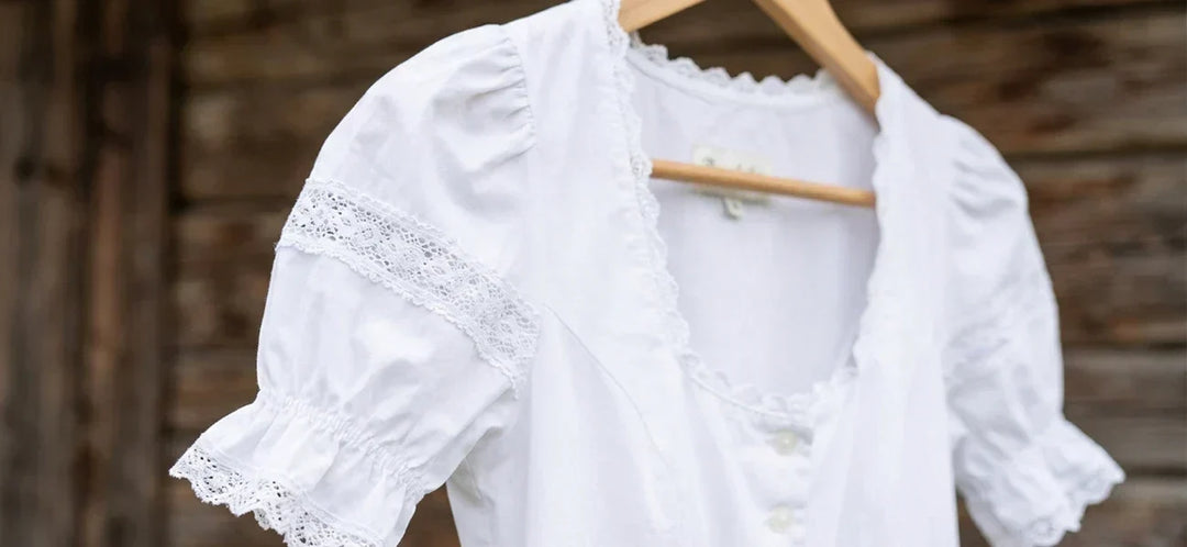 Traditional white dirndl blouse with lace detailing, puff sleeves, and decorative trim for wearing under a dirndl.